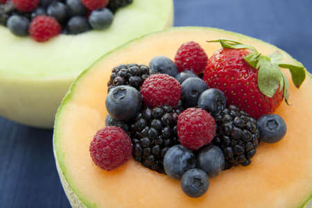 Fresh berries in a bowl made of melonの写真素材