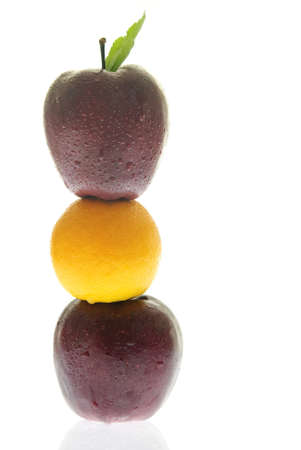 An orange in between two apples in a tower on white.の写真素材