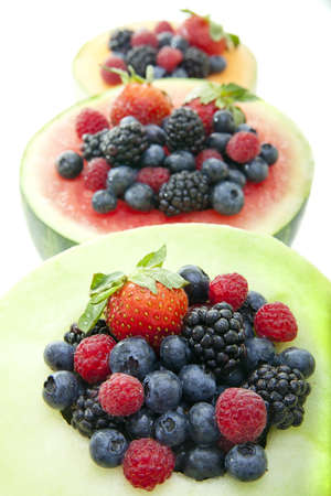 Fresh berries in melon bowls in a row.の写真素材