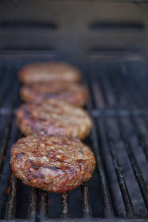 Burgers in a line cooking on the grill. Shallow DOF.の写真素材