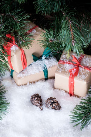Christmas theme wrapped gifts with pine tree branches on white snowの写真素材