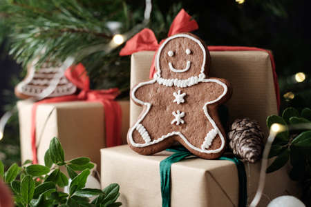 Close up photo of a Cookie man on wrapped gift boxes under a christmas treeの写真素材
