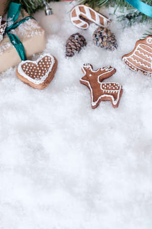 Christmas theme wrapped gifts with pine tree branches and homemade cookies on white snowの写真素材