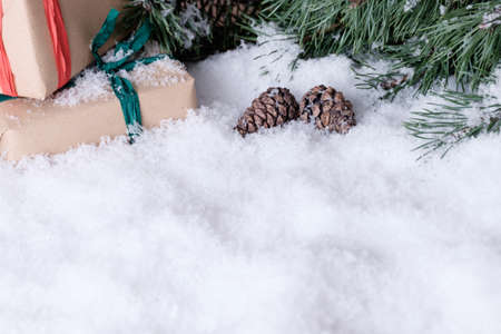 Christmas theme wrapped gifts with pine tree branches on white snowの写真素材