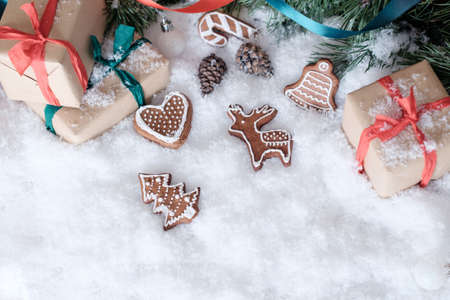 Christmas theme wrapped gifts with pine tree branches and homemade cookies on white snowの写真素材
