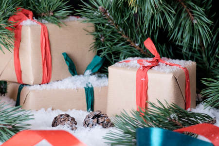 Christmas theme wrapped gifts with pine tree branches on white snowの写真素材