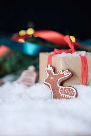 Christmas theme wrapped gifts with pine tree branches and homemade cookies on white snowの写真素材