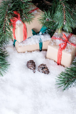 Christmas theme wrapped gifts with pine tree branches on white snowの写真素材