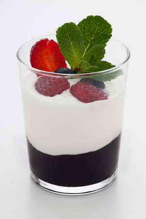 An isolated view of a recipe of fresh yogurt with blueberry jam and berries with a decorative spring of mint の写真素材
