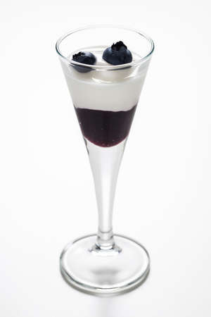 Cup of yogurt with blueberry jam and some decorative blueberries on a white の写真素材