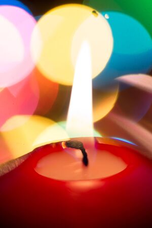 Candle in the dark close up and colored blurred lightsの写真素材