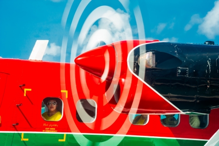 Woman looking through the porthole of Maldivian Air Taxi hydroplane ready to start in Male airport....
