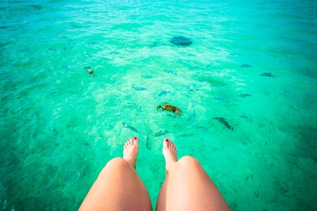 Female feet and the tropical ocean full of fish