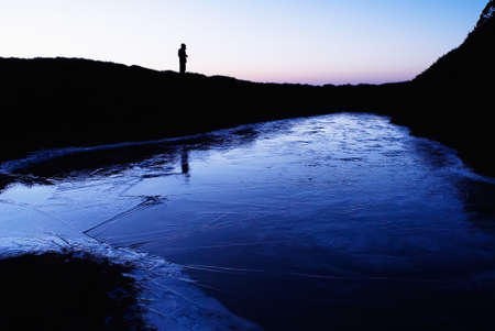 An iced lake with a man's silhouette in the morning.の写真素材