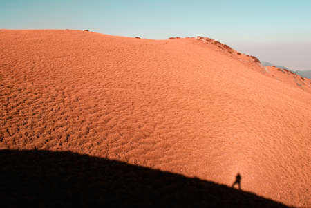 A man's shadow on the yellow grassland in high mountain.の写真素材