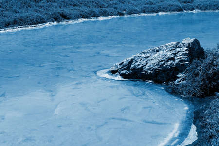 Beautiful strange iced pond surface and rock.の写真素材