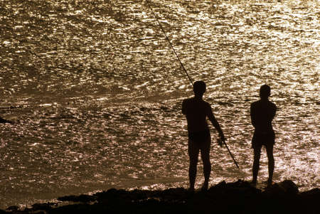 Here are two friends fishing on the rock coach.の写真素材