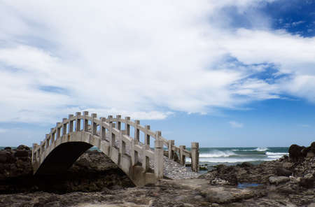 Here is a bridge on the rockland near the sea.の写真素材