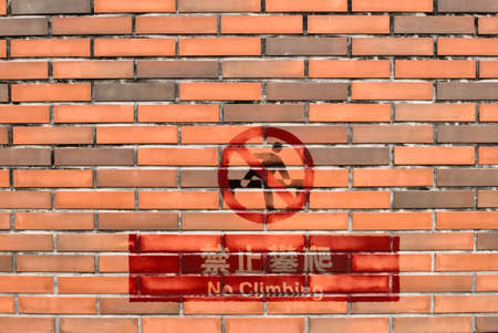 It is a red stone wall with no climbing sign in Chinese.の写真素材