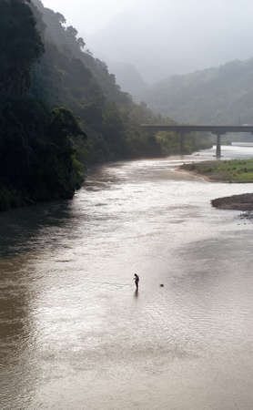 A man standed on the river and fishing.の写真素材
