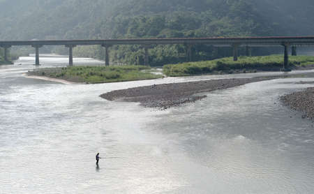 A man standed on the river and fishing.