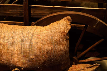It is a bag of goods lay against the wooden wheel.の写真素材