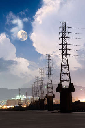 Dramatic cityscape of power tower in the night with beautiful cloud and moon near river.の写真素材