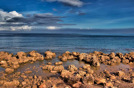 It is nature beach of ocean full of rock with blue sky.の写真素材