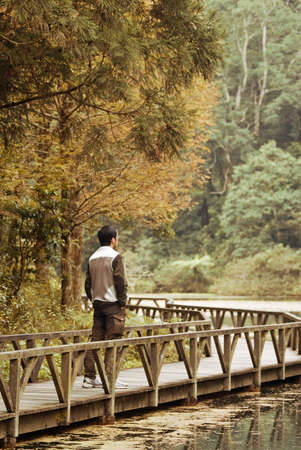 Man stand on bridge near the lake in beautiful forest.の写真素材
