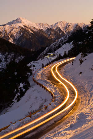 Car light in night on ice road in snow winter mountain.の写真素材