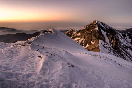 Mountain scenery with snow slop and dramatic peak in dusk sunset evening.の写真素材