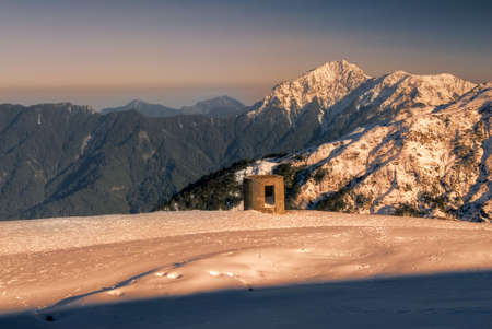 Beauty of snow mountain with blockhouse in yellow sunset.の写真素材