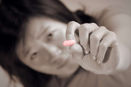 Sick woman holding pill with pain face.の写真素材