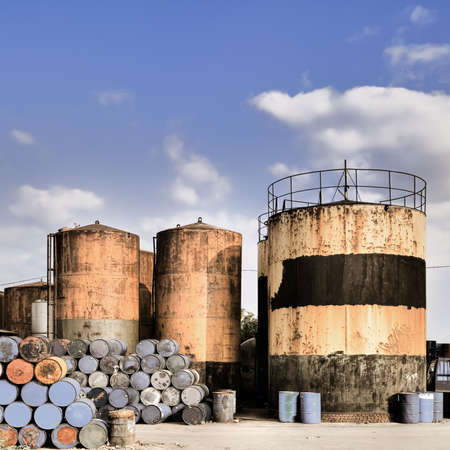 Industrial factory tower in yellow with oil drum in blue under sky.の写真素材