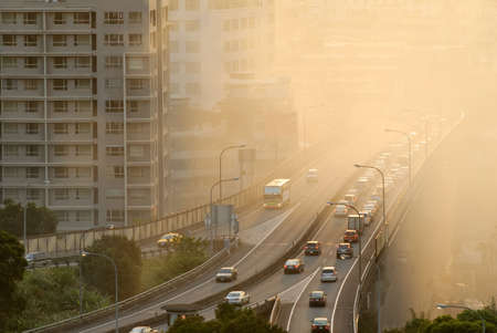 Air pollution scenic with cars on highway and yellow smoke in city.の写真素材