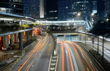 Traffic in city with cars motion blurred light and office building in night.の写真素材