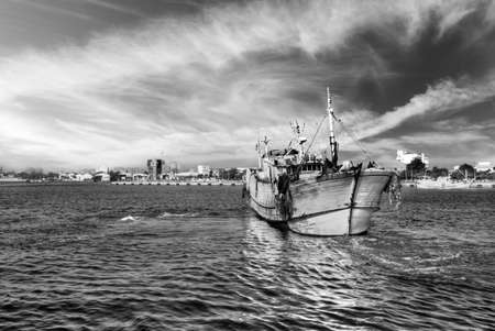 Dramatic landscape of harbor with one boat on water.の写真素材