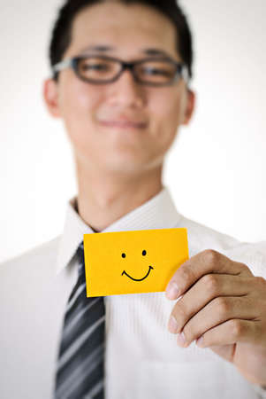 Smile pattern on yellow card hold by business man.の写真素材