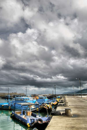 Bad weather of storm in harbor with fishing boats on pier.の写真素材