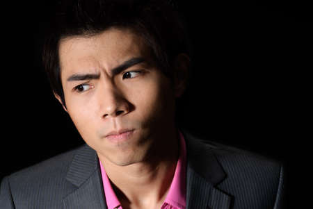 Young businessman thinking, closeup portrait in dark background.