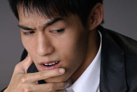 Sly business man of Asian, closeup portrait over studio gray background.の写真素材
