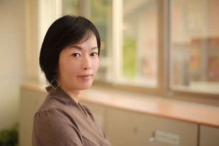 Kindly Asian woman face, closeup portrait indoor.