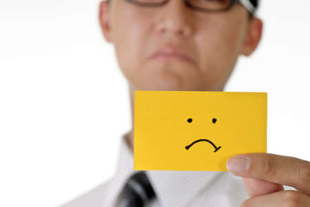Worried sign on yellow card holding by worried young man.の写真素材