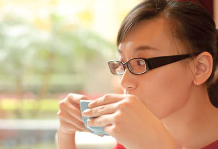 Asian lady drink a cup of coffee in restaurant in daytime.の写真素材