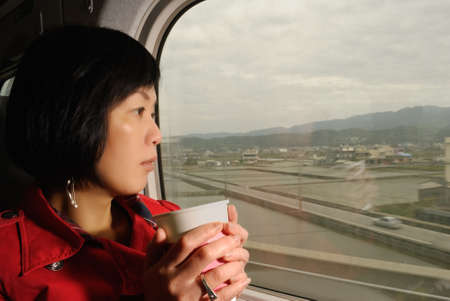 Traveler woman of Asian in train looking outside of window, half length closeup portrait indoor.の写真素材