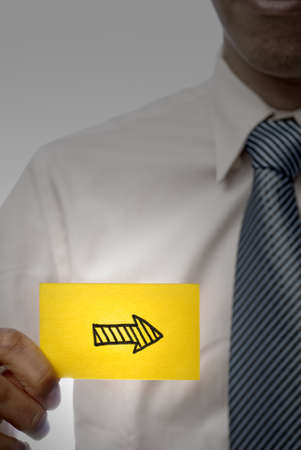 Business man holding right arrow shape on yellow card, closeup portrait.