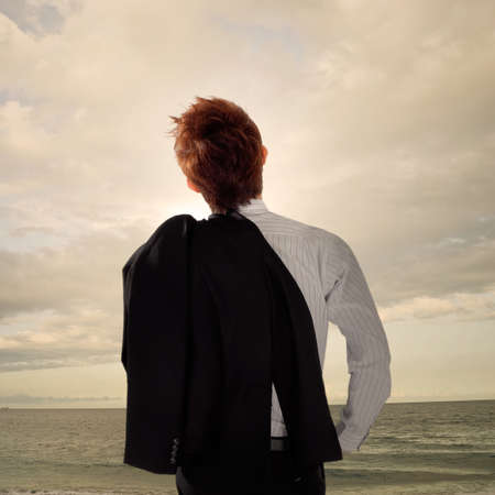 Tired business man standing in outdoor and looking far away of ocean.の写真素材
