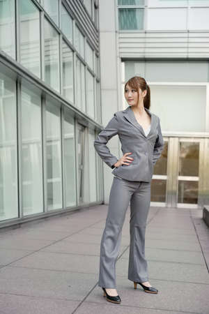 Confident business executive standing and looking, full length portrait outside of modern buildings.の写真素材