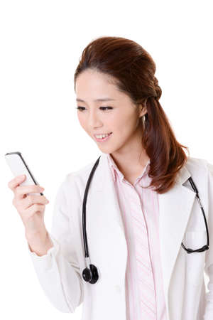 Friendly Asian doctor woman check message on cellphone, closeup portrait isolated on white background.の写真素材