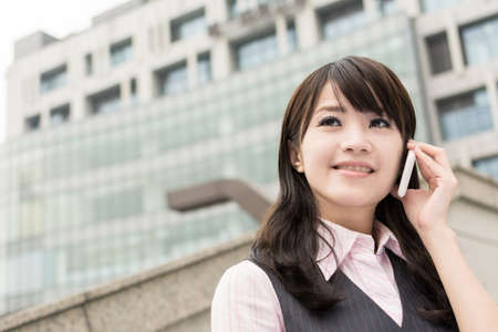 Business woman of Asian talk on cellphone, closeup portrait in urban.の写真素材